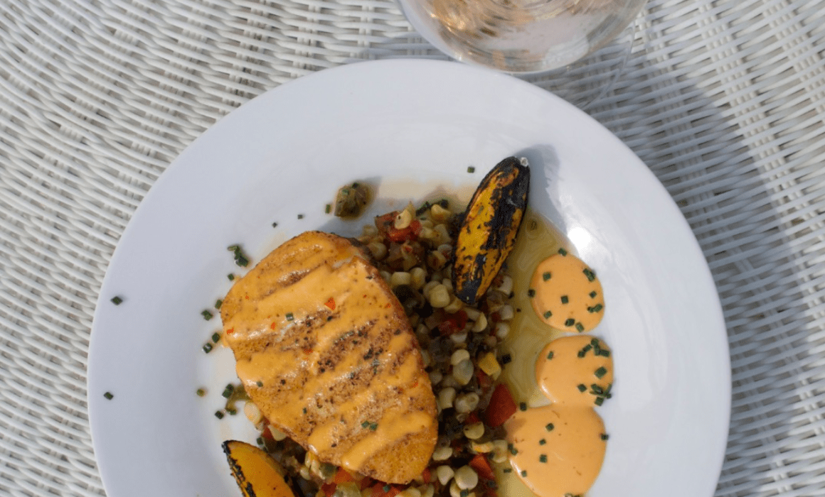 Gourmet salmon dish with roasted vegetables, grains, and creamy sauce served at Villa San Juliette