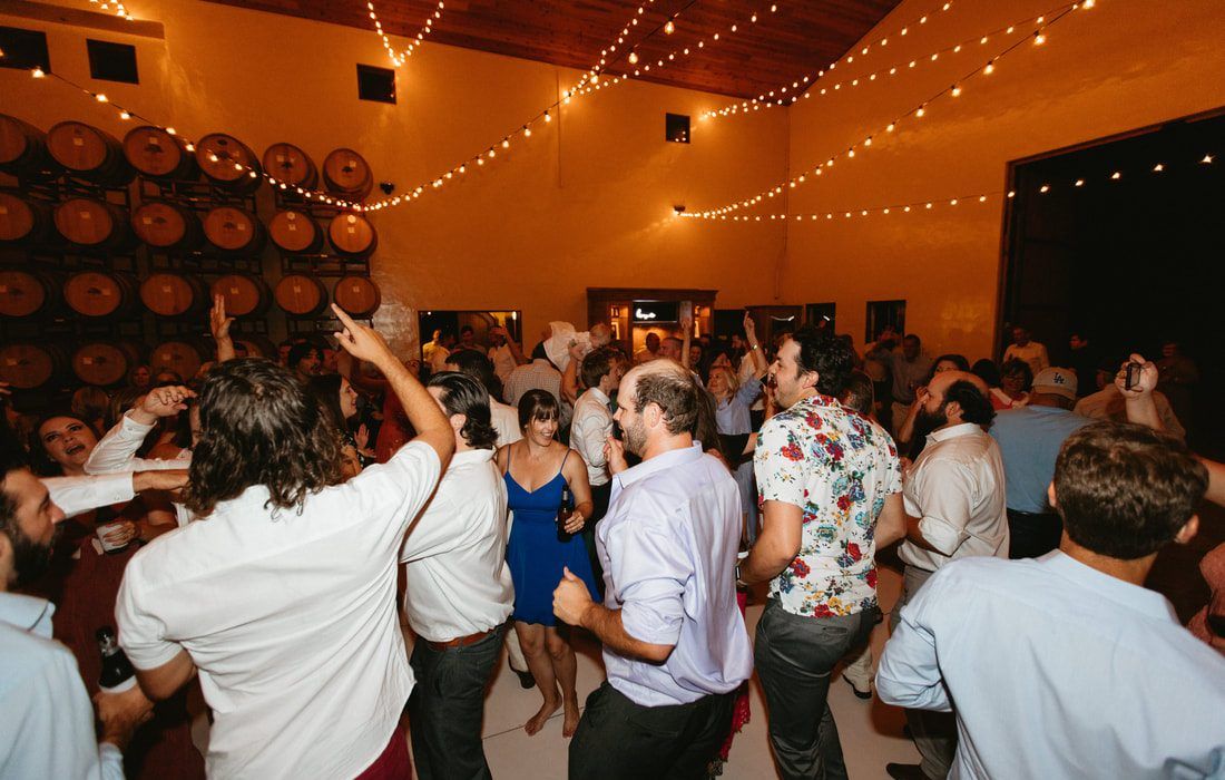 Guests dancing and celebrating together at a lively private event reception with warm string lights and festive indoor décor.