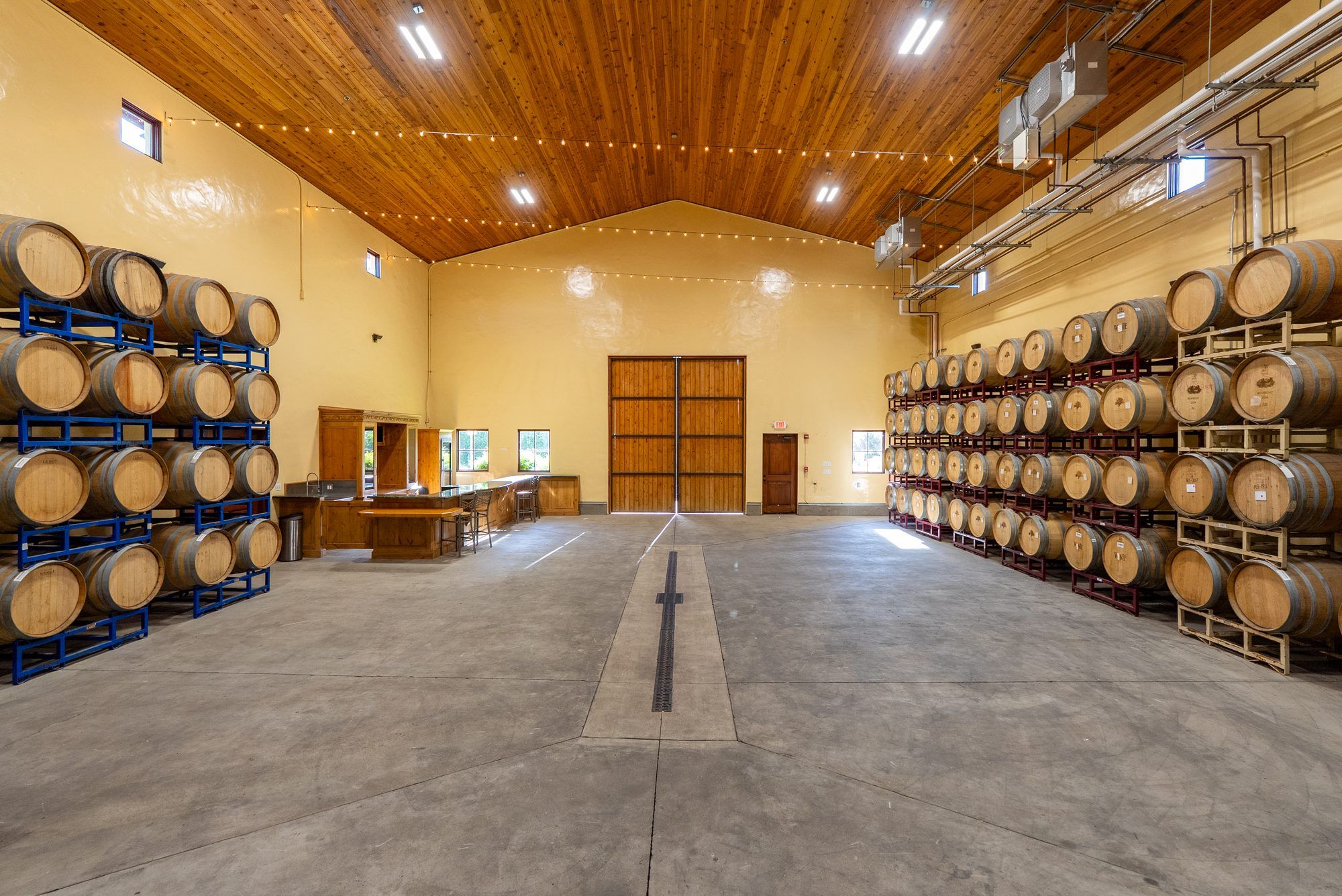 Barrel room at Villa San-Juliette with oak wine barrels beneath a warm wood ceiling